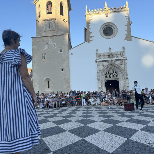 Agro the clown. ImproLocura. Agro performing in the square surrounded by the audience with a church in the background. Luca Della Gatta