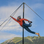 Playground, solo lunaire et chaleureux de Miguel Rubio, mêlant mât chinois et arts du cirque, avec un système d’accroches collaboratives. On en sort avec le sourire aux lèvres et le soleil au cœur. spectacle familial adapté à tous les publics. Miguel Rubio sur un mât chinois avec des arbres en arrière-plan.